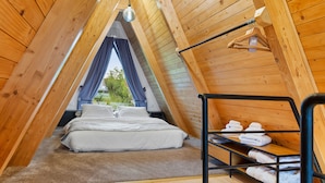 A cozy attic bedroom with a bed, a small table, and a shelf with towels. - Three-Bedroom A Frame Chalet in Dealu Mare (Malu Roșu)