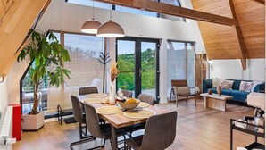 A modern interior with a dining area, a sofa, and a piano. - Three-Bedroom A Frame Chalet in Dealu Mare (Malu Roșu)