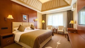 A hotel room with a large bed, bedside tables, a desk, and a chair. - Jiaozishan Resort Hotel (Luquan)