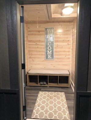 Un interior de madera con un cartel que dice 'WELCOME', un banco y una alfombra estampada.