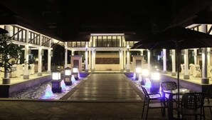 Entrada de hotel com um recurso de água, área de estar externa e galeria coberta.