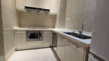 A compact kitchen with a built-in oven, dishwasher, and a stainless steel sink.