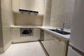 Una cocina compacta con horno integrado, lavavajillas y pileta de acero inoxidable.