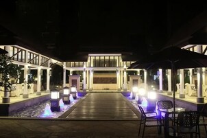 A hotel entrance with a water feature, outdoor seating, and a covered walkway.