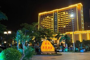 A hotel with a modern facade, illuminated by yellow lights, and a prominent sign in front.