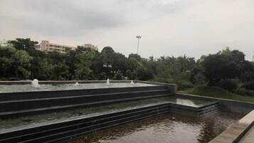 A tiered water feature with multiple fountains, surrounded by a landscaped garden and trees.