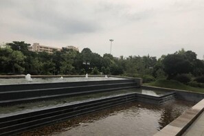 A tiered water feature with multiple fountains, surrounded by a landscaped garden and trees. - Lotin Hot Springs Hotel (Gaozhou)