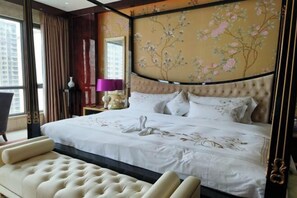 Un dormitorio con una cama grande, un cabecero tapizado, un panel decorativo en la pared y vistas a la ciudad.