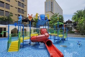 Un parque infantil con un tobogán rojo y diversas estructuras de juego.