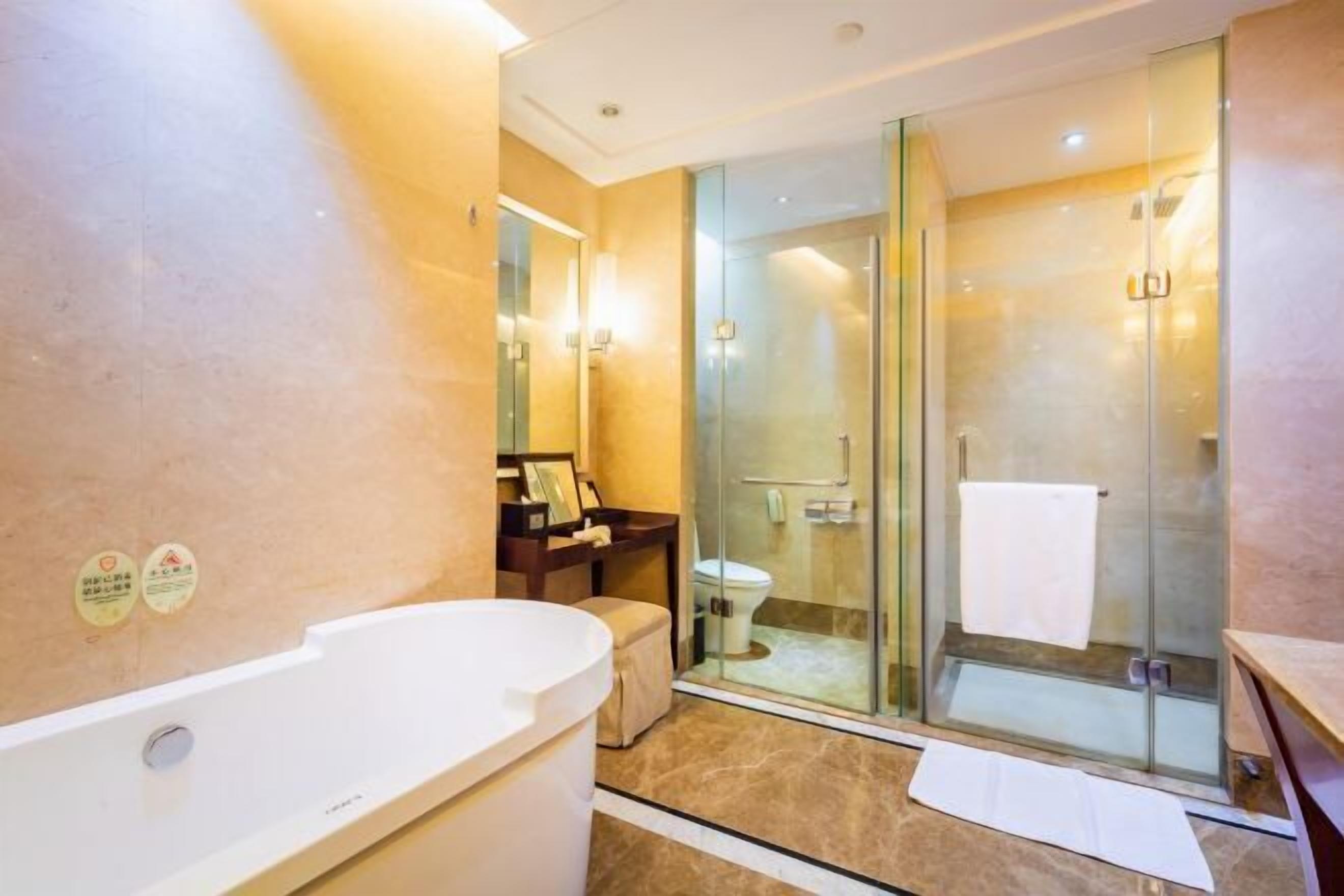 Un baño moderno con cabina de ducha de vidrio, una bañera blanca y un lavamanos con espejo.