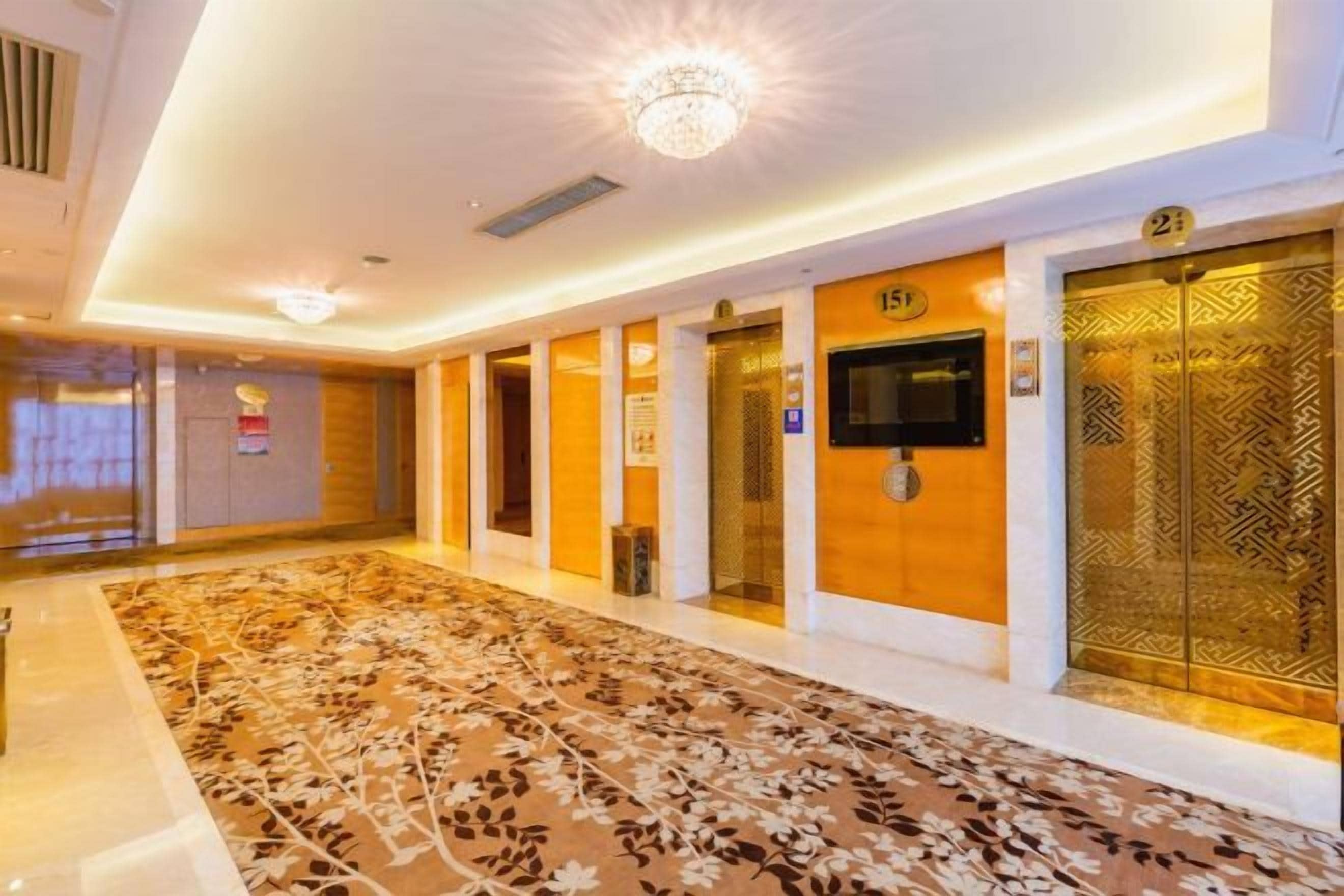 Pasillo de hotel con alfombra estampada, ascensores y una zona de recepción.