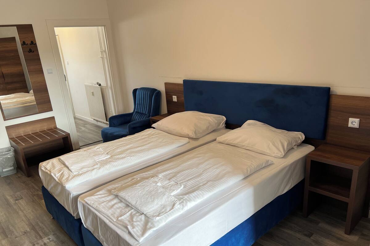Una cama doble con ropa de cama blanca, un cabecero azul y una mesita de noche de madera.