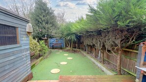A backyard with a wooden deck, a fenced area, and a small shed.