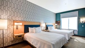 A hotel room with two beds, a patterned wall, a large window, and a nightstand with a lamp. - Home2 Suites By Hilton Livermore (Livermore)