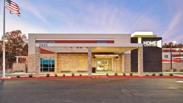 A modern hotel entrance with a covered outdoor area, a flag, and a clear sky.