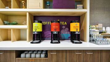 Estación de café y té con tres dispensadores etiquetados como Descafeinado, Agua Caliente y Gourmet.