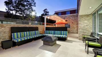 Un espace extérieur aménagé avec un patio, un canapé d’angle, un coin salon abrité et une table à manger avec des chaises.