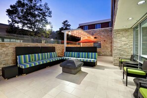 Un espace extérieur aménagé avec un patio, un canapé d’angle, un coin salon abrité et une table à manger avec des chaises.