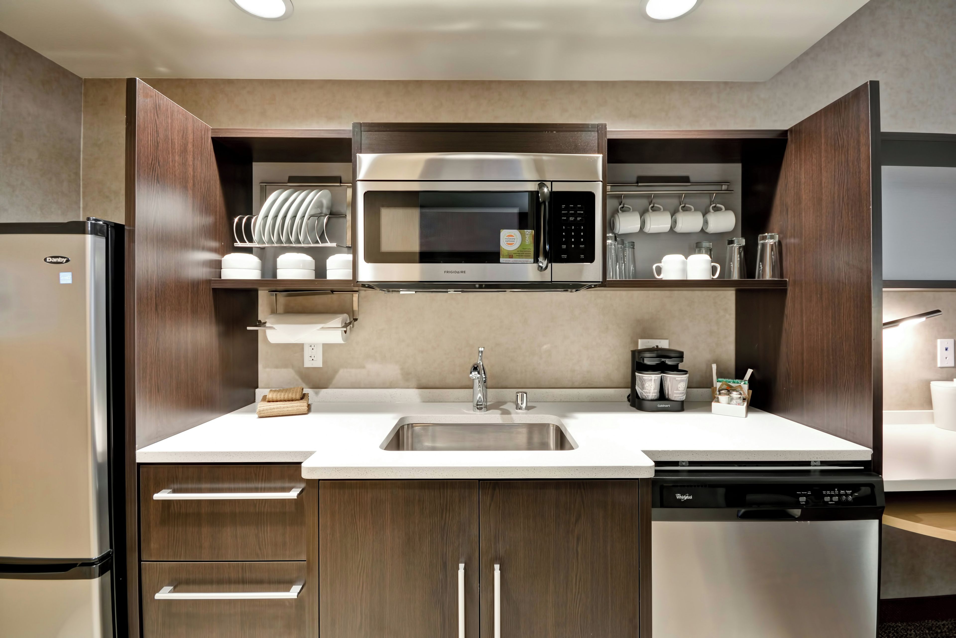 Una cocina moderna con microondas integrado, pileta de acero inoxidable y lavavajillas.