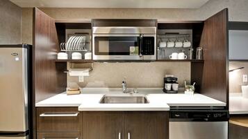 Una cocina moderna con microondas integrado, pileta de acero inoxidable y lavavajillas.