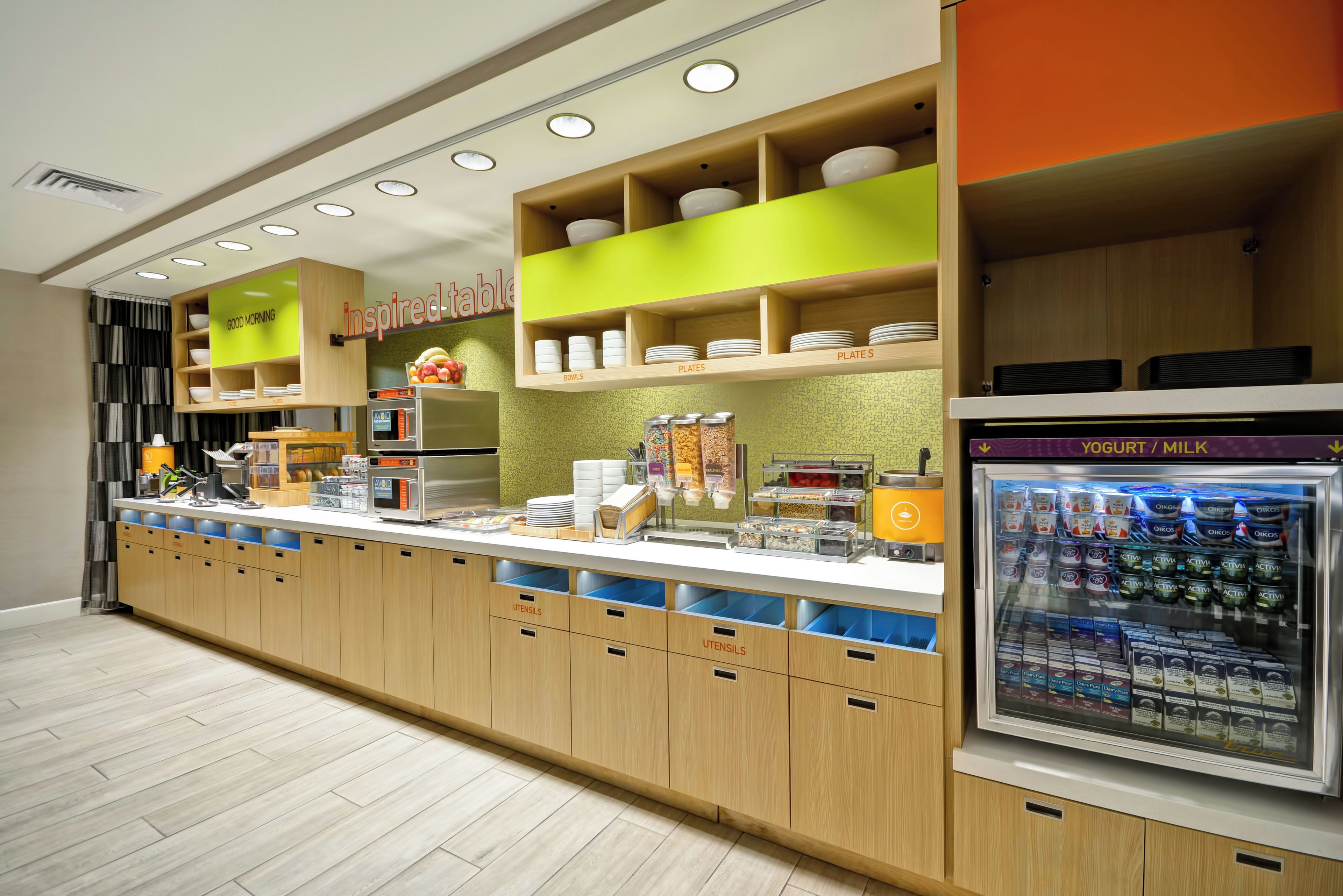 Un bar à petit-déjeuner moderne avec un espace en libre-service, comprenant des bols, des assiettes et des couverts.