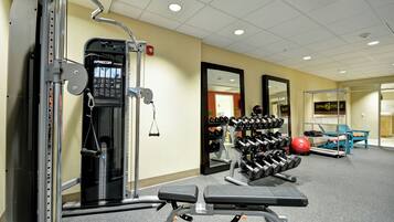A gym with weightlifting equipment, a bench, and a mirrored wall.