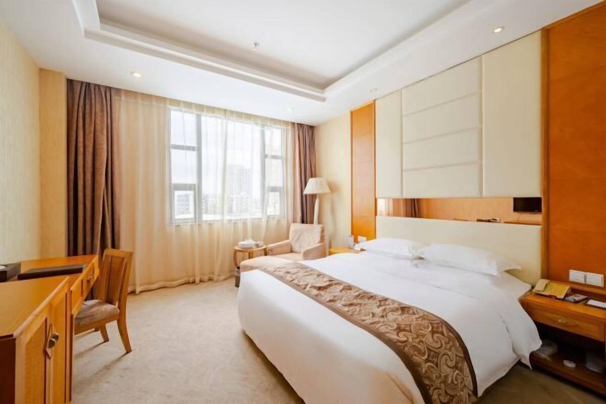 Una habitación de hotel con una cama grande, un escritorio, una silla y una mesita de noche.