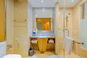 Un baño con cabina de ducha de vidrio, lavabo con espejo e inodoro.