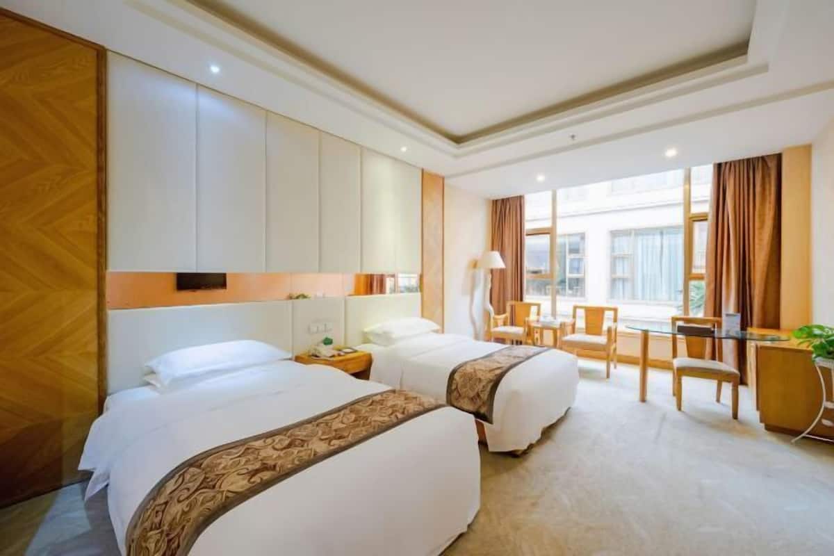 Habitación de hotel con dos camas, un escritorio y una silla.