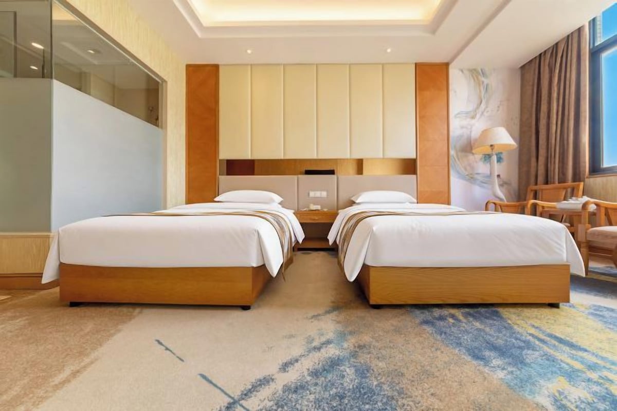 Una habitación de hotel con dos camas, un ventanal grande y vistas a la ciudad.