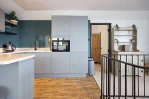 A modern kitchen with grey cabinets, a wooden floor, and a black railing.