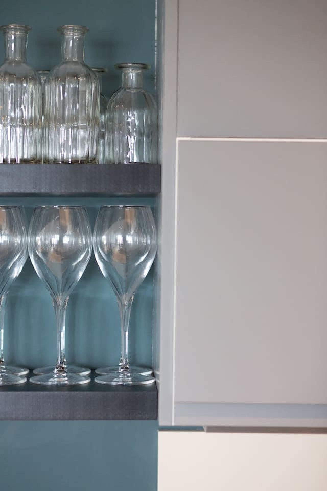 A kitchen shelf with glassware and bottles.