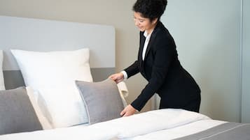 A hotel room with a neatly made bed, a large window, and a modern design.