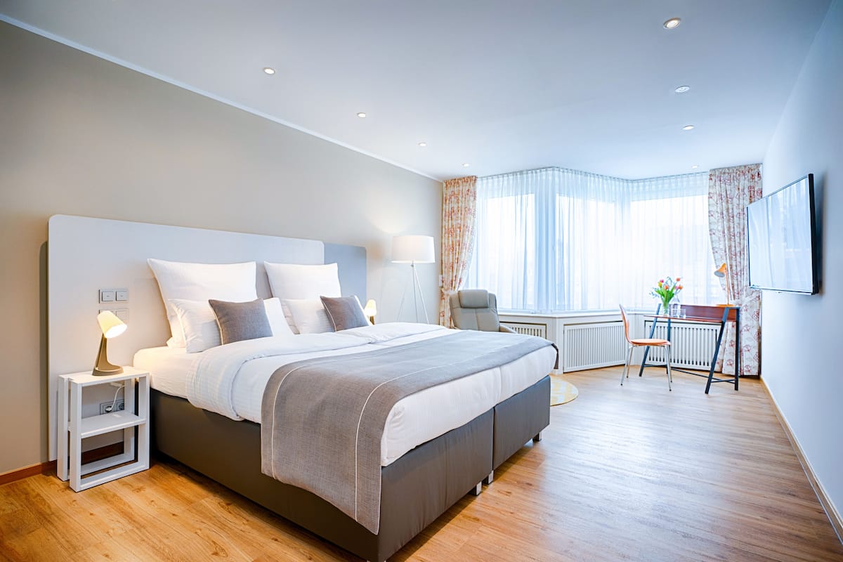A modern bedroom with a large bed, bedside tables, a desk, and a chair.