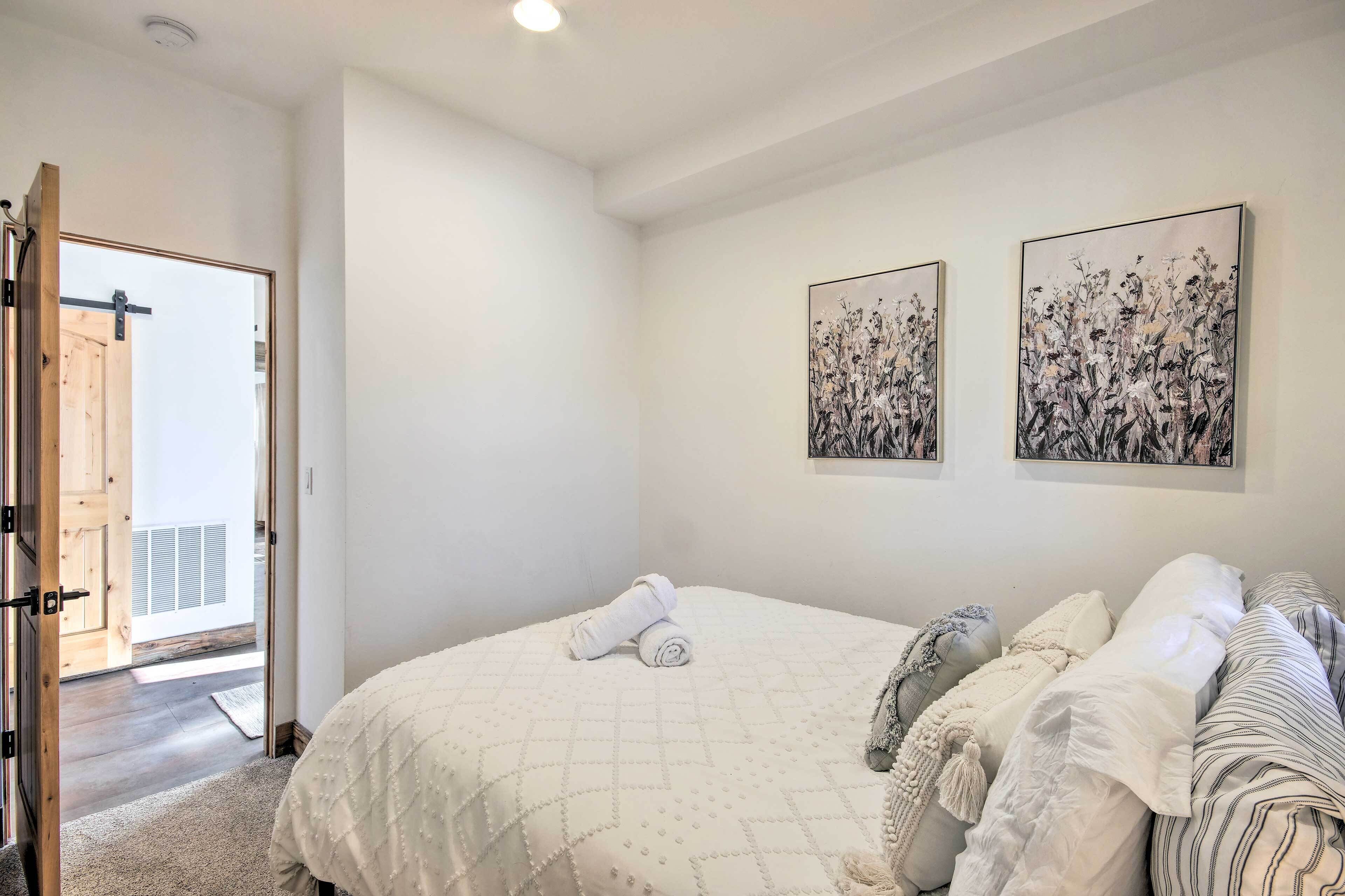 Une chambre avec un lit, deux œuvres d’art accrochées au mur et une porte donnant sur un espace extérieur.