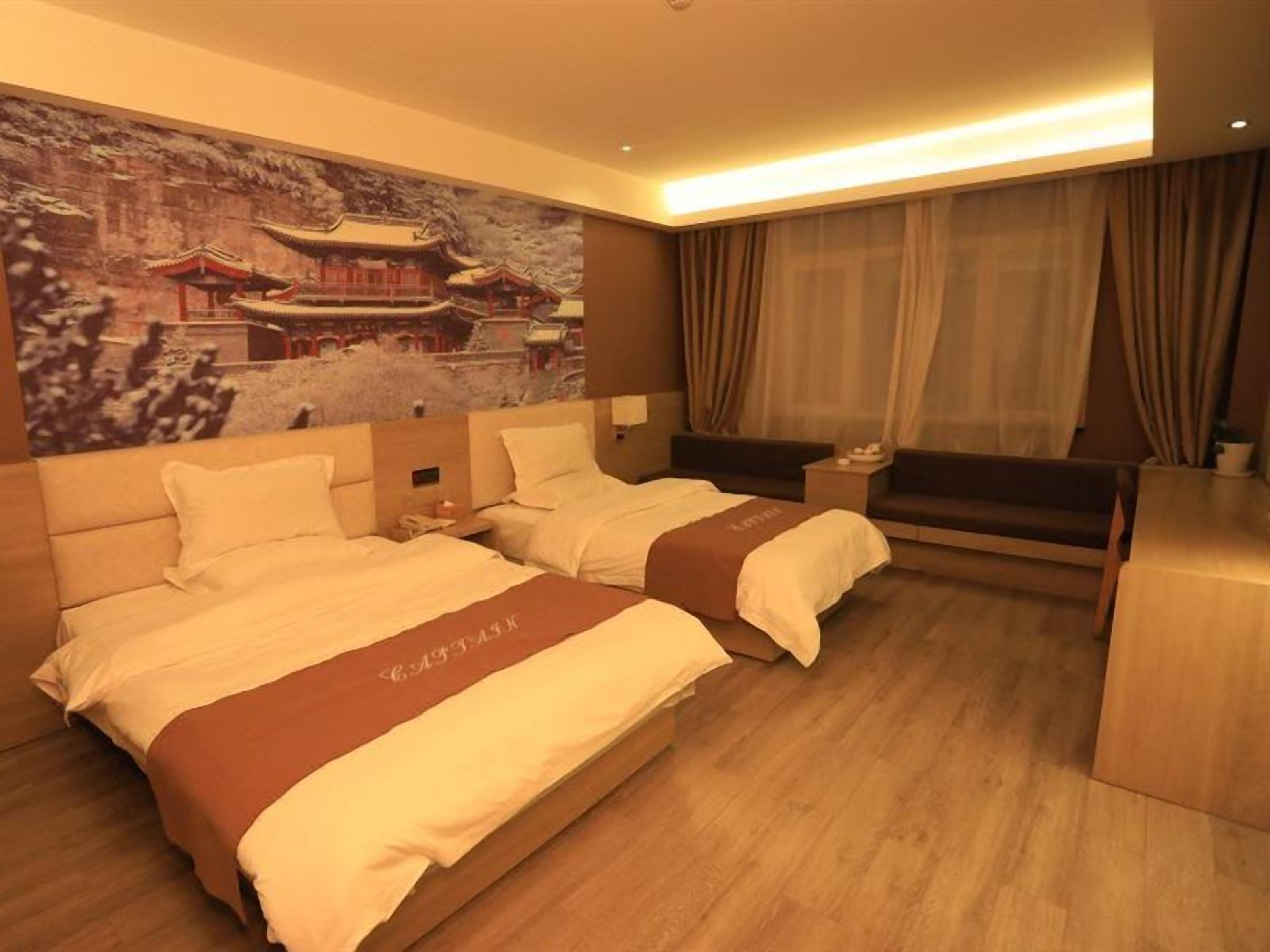 A hotel room with two beds, a large wall painting, a desk, and a sofa.