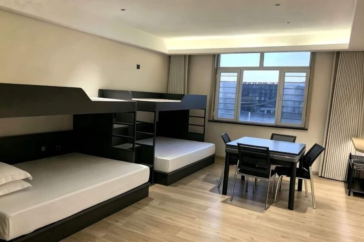 Una habitación con literas, un escritorio, sillas y una ventana con vistas.
