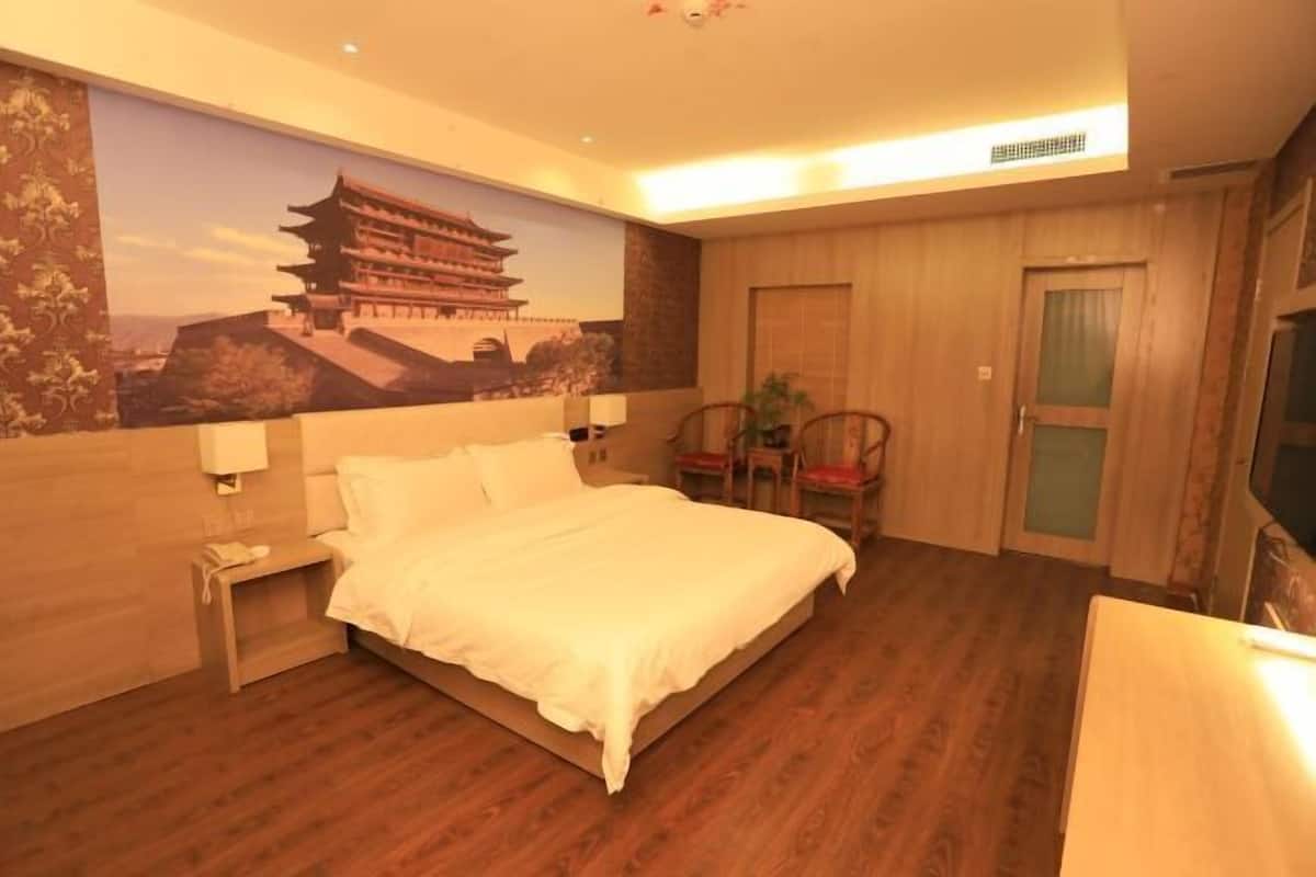 Un dormitorio con cama, mesita de noche, silla y televisor instalado en la pared.