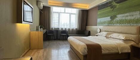 Quarto de hotel moderno com uma cama grande, uma mesa de trabalho e vista para uma paisagem verde.