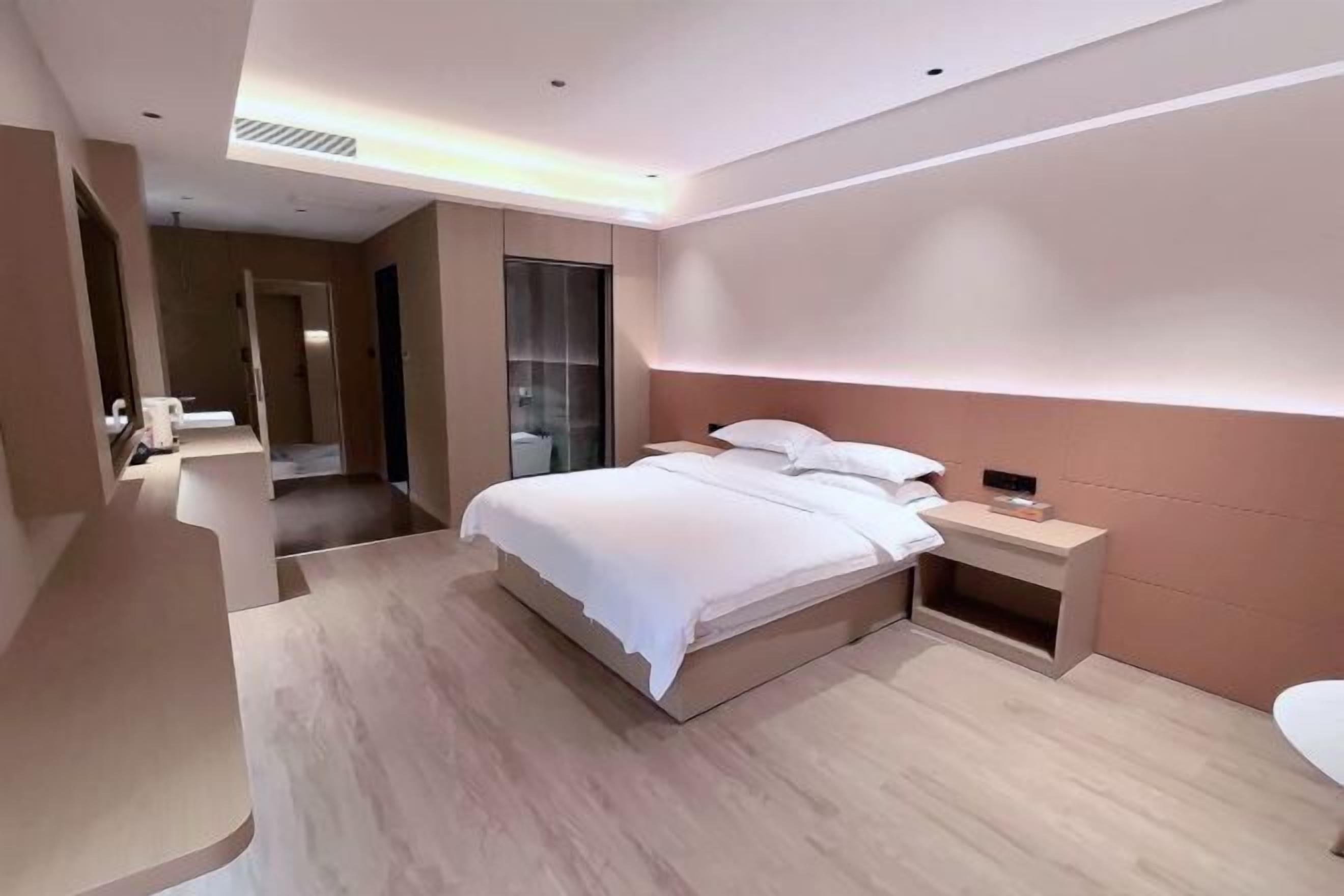 A modern hotel room with a large bed, bedside tables, a mirror, and a bathroom.