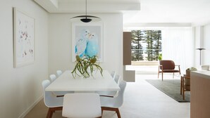 Un comedor moderno con una mesa blanca, sillas y un centro de mesa con planta.