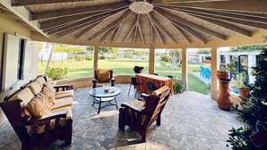 A covered patio area with a wooden ceiling, stone flooring, and outdoor furniture. - Donhenri House Hodges Bay in Antigua (Saint John's)