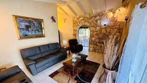 A living room with a stone wall, a sofa, a coffee table, and a painting on the wall. - Donhenri House Hodges Bay in Antigua (Saint John's)