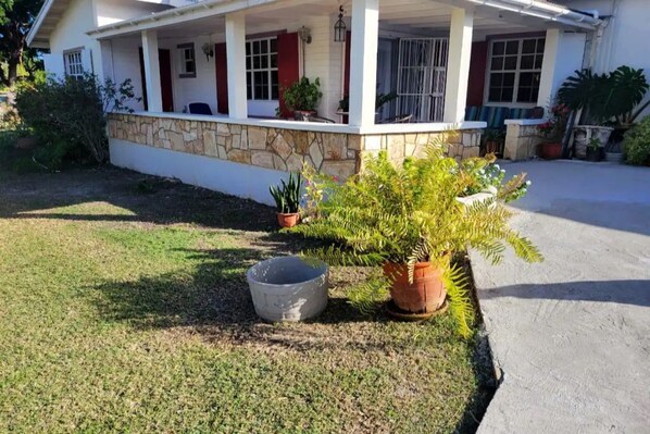 A house with a covered porch, stone foundation, and potted plants.