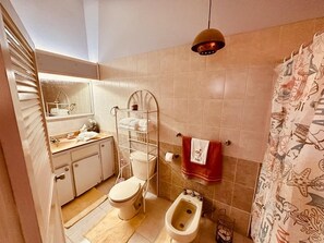 A bathroom with a toilet, bidet, and a towel rack.