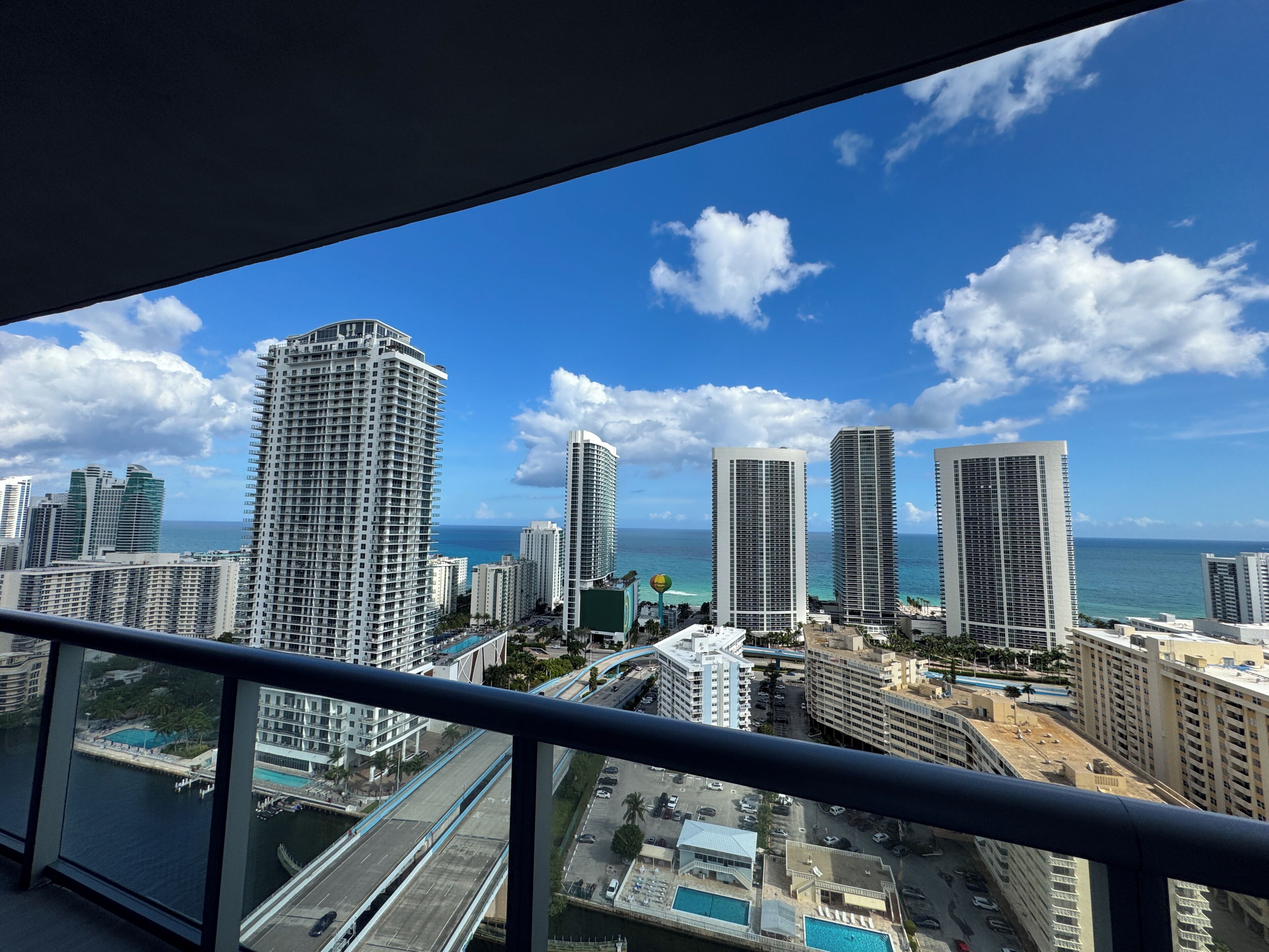 A cityscape with high-rise buildings, a bridge, and a view of the ocean.