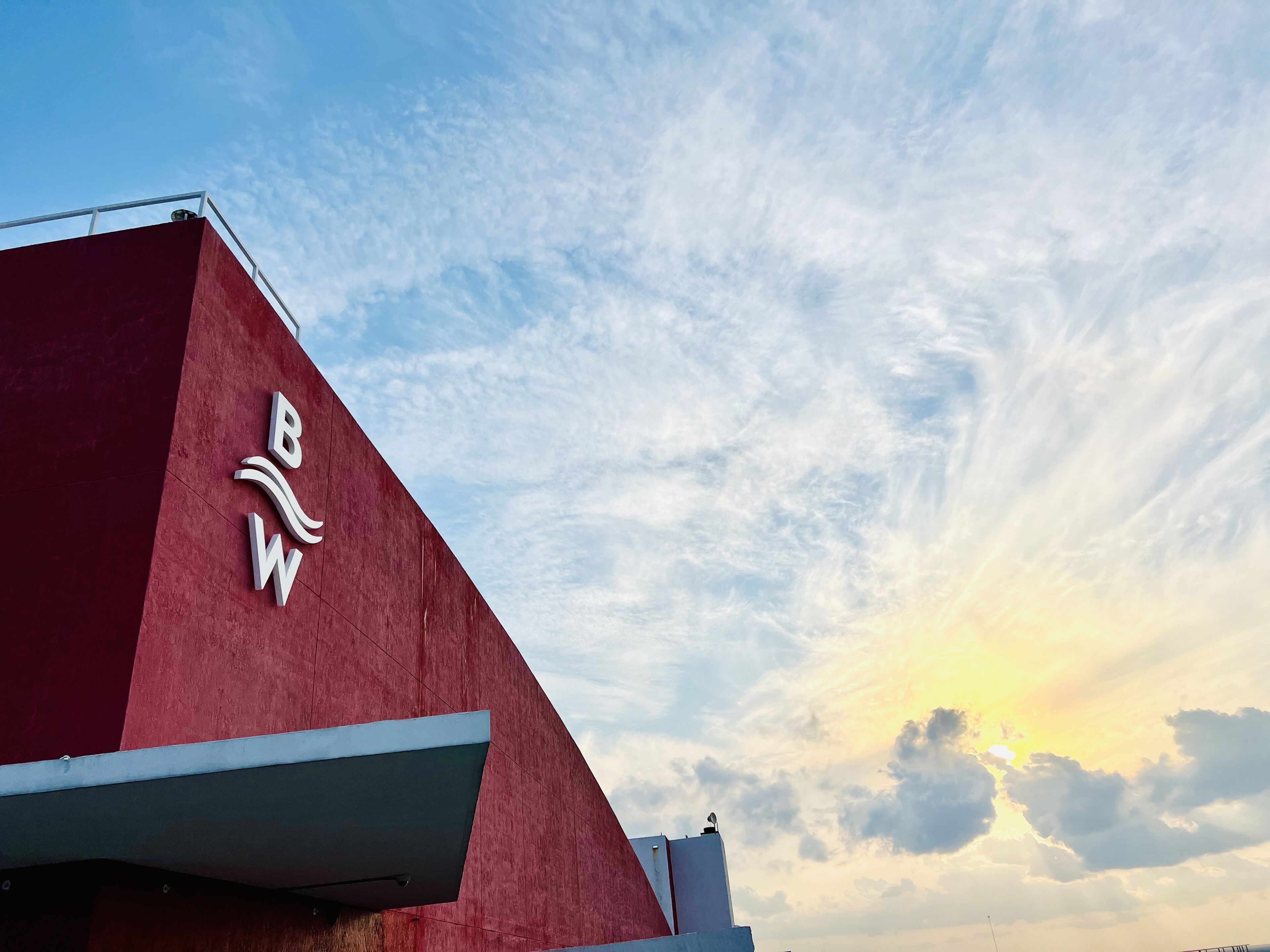 Un edificio con fachada roja y un cielo despejado con nubes.