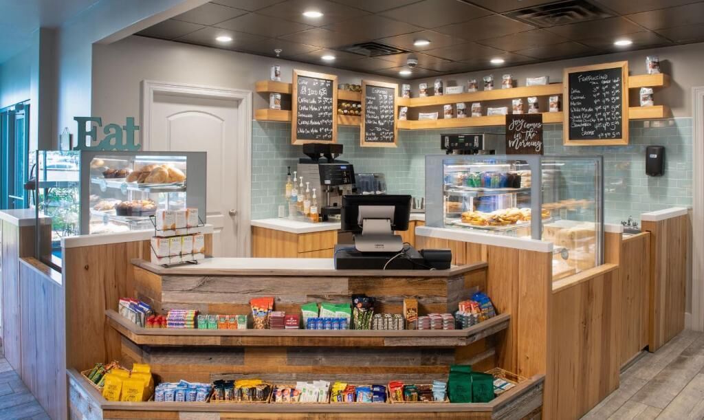 Un comptoir de boulangerie avec une machine à café, des étagères remplies de produits de boulangerie et un tableau noir affichant le menu.