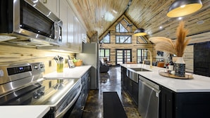 Cocina moderna con electrodomésticos de acero inoxidable, techo de madera y ventanas amplias.