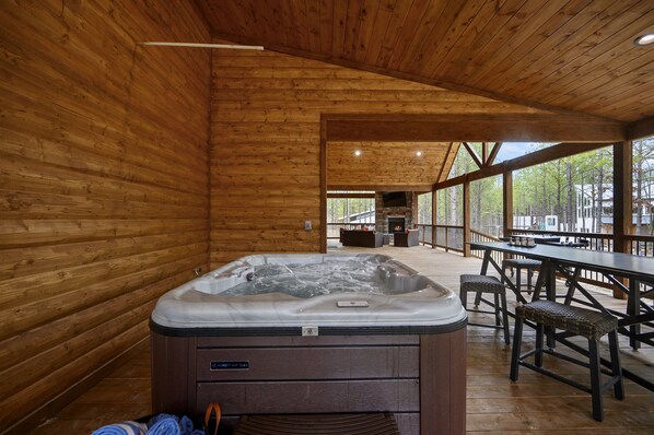 A wooden cabin interior with a hot tub, wooden deck, and outdoor seating area.
